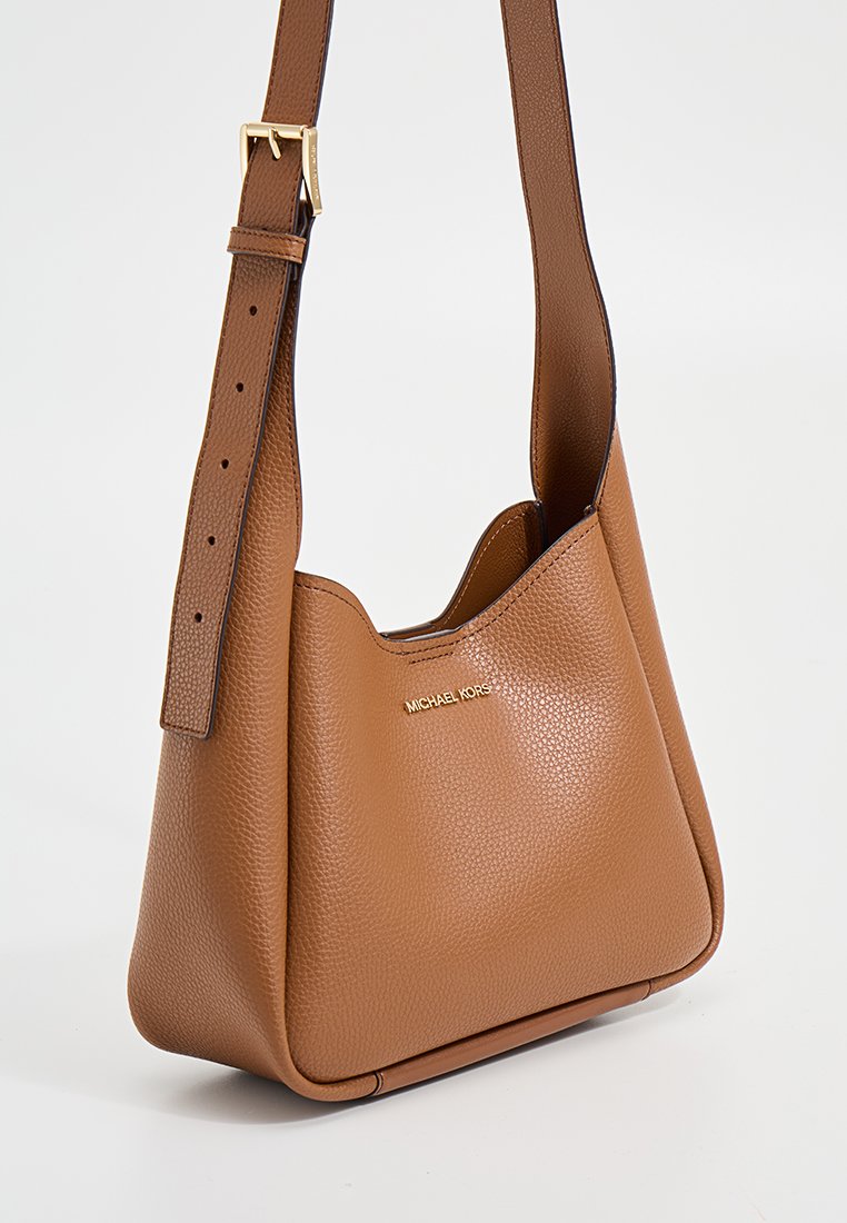 Bruine leren schoudertas met een gepolijste textuur, een gouden logo-accent en een verstelbare band. Het ontwerp is zacht en slungelig.