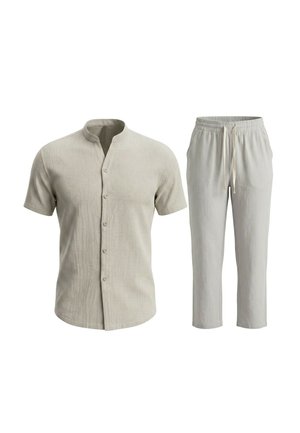 Beige overhemd met korte mouwen, mandarijnkraag en knopen, gecombineerd met bijpassende broek met elastische taille en trekkoord.