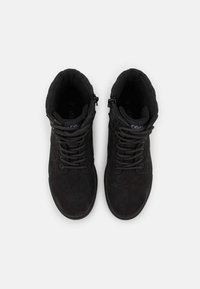 Botas negras de tobillo con textura de gamuza, que cuentan con un collar acolchado, cordones redondos y una cremallera lateral. La etiqueta dentro de la bota dice "37".
