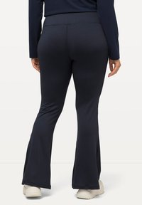 Pantaloni a palazzo blu navy realizzati in un tessuto morbido e elasticizzato con una vita alta. Presentano un design pulito e semplice, senza motivi o decorazioni.