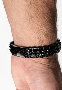 Black braided leather bracelet featuring a glossy black metal clasp, showcasing a woven texture and smooth finish.