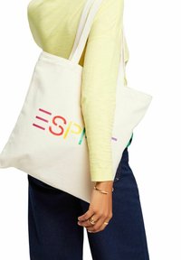 Canvas-Shopper in Off-White mit mehrfarbigem "ESPRIT"-Aufdruck. Verfügt über robuste Schulterriemen und hat eine schlichte rechteckige Form.