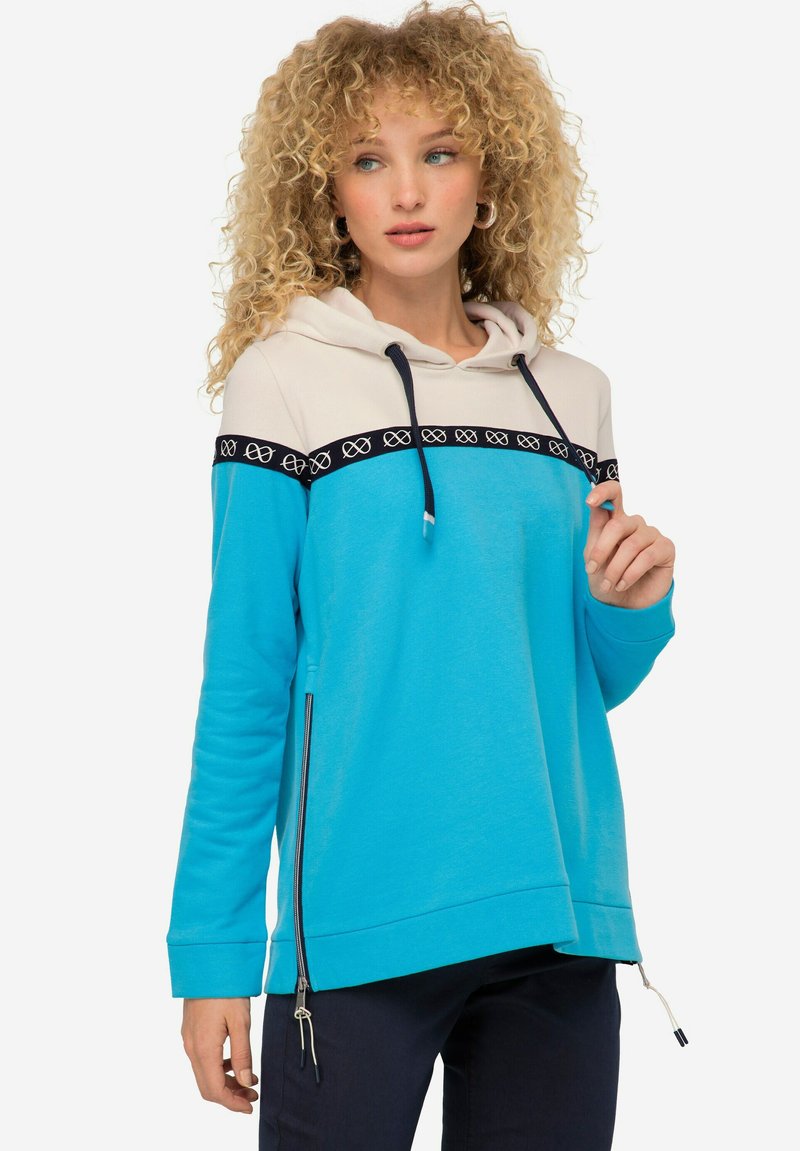 Sweat à capuche bleu et crème avec un détail de fermeture éclair à l'avant, une bande noire à motifs sur la poitrine, des cordons de serrage et une coupe décontractée.