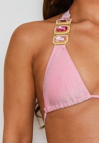 Rosa Bikini-Oberteil mit schimmernder Textur, das eine dreieckige Form aufweist und dekorative Träger hat, die mit großen rosa Edelsteinen und goldenen Akzenten verziert sind.