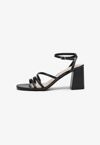 Black heeled sandals with multiple thin straps, square toe, and a block heel, featuring an adjustable ankle strap. Smooth leather texture.