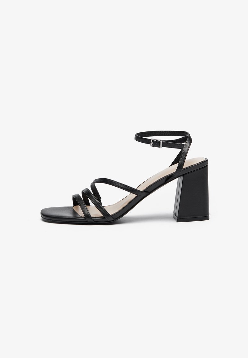 Black heeled sandals with multiple thin straps, square toe, and a block heel, featuring an adjustable ankle strap. Smooth leather texture.
