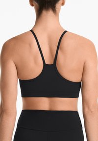 Zwarte sportbeha met een racerback ontwerp, een soepele textuur, minimale stiksels en logo-detail op de achterkant.