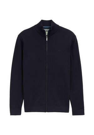 Marineblauwe zip-up jas met een hoge kraag, ribgebreide boorden en onderkant, gladde brei-textuur, met een klein logo aan de linkerkant.