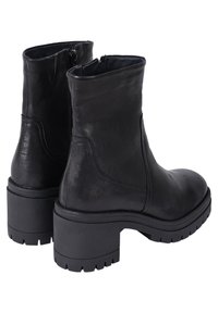 Mustat nahkaiset nilkkurit, joissa on pyöristetty kärki, sivuvetoketju ja paksu kumipohja, jossa on urituspatteri pidon parantamiseksi.