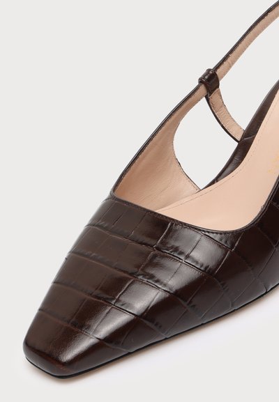 Chaussure marron foncé à bout carré, à texture effet crocodile et bride arrière, présentée en gros plan sur fond clair.