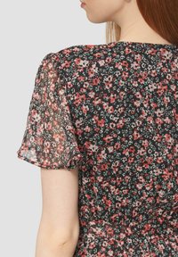 Robes fleuries avec des manches courtes et transparentes. Tissu noir avec de petites fleurs rouges, roses et vertes. Taille froncée avec une jupe fluide.
