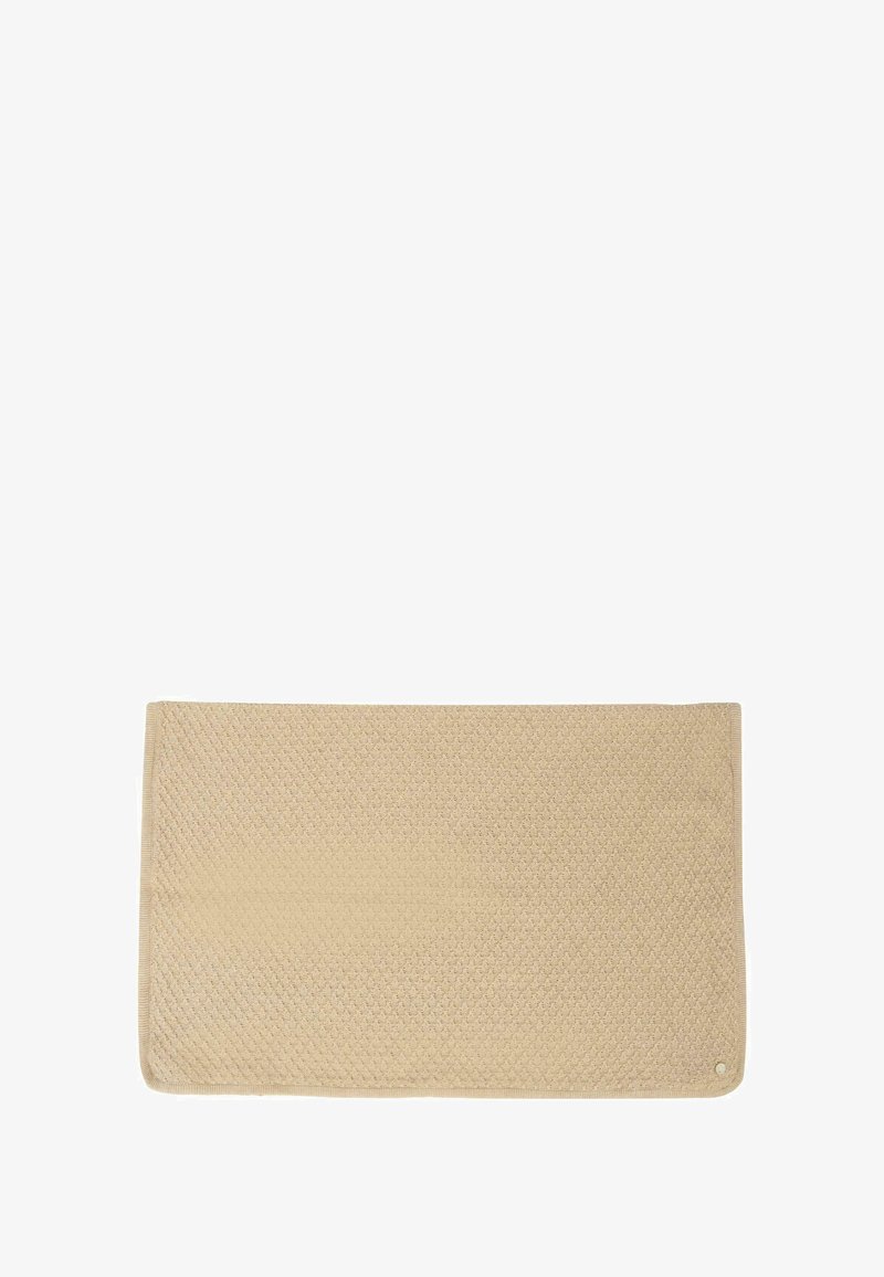 Beżowy prostokątny dywanik o fakturowanej powierzchni, z wzorem w diamenty, wykończony gładką krawędzią oraz małym okrągłym akcentem.