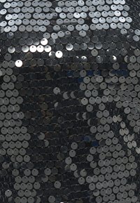 Μαύρο ύφασμα πυκνά καλυμμένο με μικρές λαμπερές ασημί παγιέτες που αντανακλούν το φως σε διασκορπισμένα σχέδια.