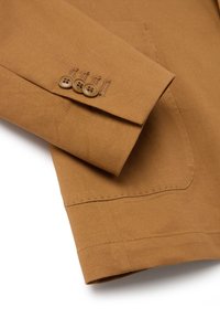 Manica di giacca di cotone marrone con tre bottoni rotondi marroni, dettagli di cucitura visibili e una tasca singola. Texture liscia con design su misura.