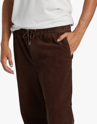 Brown corduroy pants with an elastic waistband and drawstring. Features side pockets and a textured, ribbed surface.