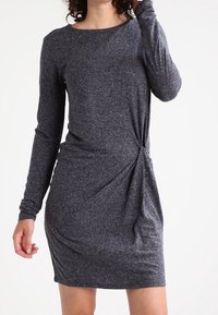 Langärmliges graues Kleid aus strukturiertem Stoff, mit einer verdrehten Detailanpassung an der Taille und einem runden Ausschnitt, geeignet für legere Anlässe.