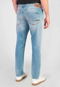 Lichtblauwe denim jeans met een rechte pasvorm, vijf zakken en een tan leren label op de achterste tailleband. Smooth textuur met vervaagde accenten.