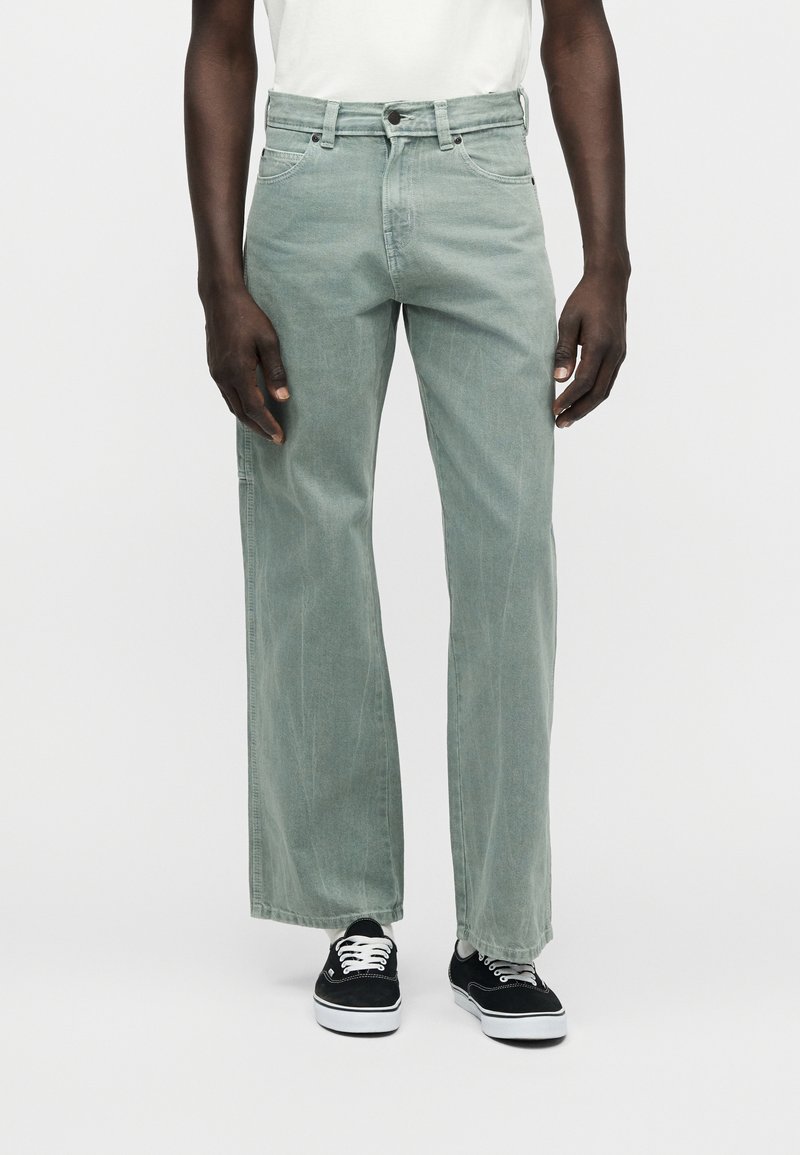 Lichtgroene denim jeans met een rechte pasvorm, vijfzakkenontwerp en vervaagde textuur. Gecombineerd met zwarte sneakers en een wit T-shirt.