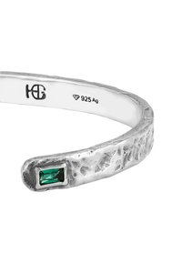 Silverarmband med en strukturerad, hamrad yta. Har en rektangulär grön sten som accent. Märkt 925 Ag för äkthet av sterlingsilver.