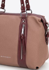 Brązowa torebka z teksturowanej tkaniny z burgundowymi skórzanymi akcentami, z zapinaną na zamek przednią kieszenią i srebrnymi detalami. Widoczne logo marki.