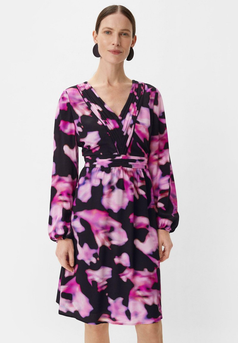 Schwarz mit floralem Muster, in verschiedenen Rosa-Tönen. Lange Ärmel, V-Ausschnitt, gedehnte Details an der Brust und tailliert.