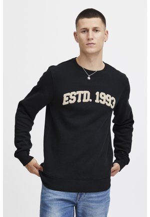 Sudadera negra con cuello redondo y puños de canalé, con "ESTD. 1993" bordado en beige en la parte frontal. Material suave y corte clásico.