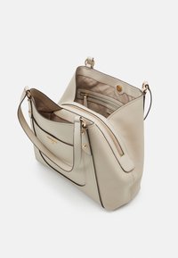Romantische leren handtas in crème met gouden rits en drukknoopsluiting, verstelbare schouderriem en beige gevoerd interieur met een ritszak.
