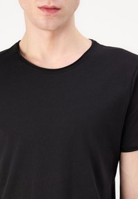 Black short-sleeve T-shirt with a round neckline, made of soft fabric, featuring a smooth texture and minimal stitching details.