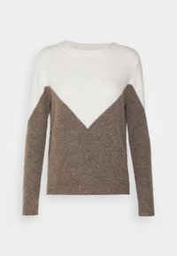 Långärmad tröja med en vit överdel som bildar en V-form, och brunt texturerat tyg som täcker resten av kroppen och ärmarna.