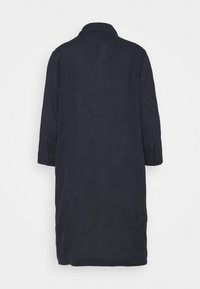 Manteau long bleu marine foncé avec manches longues, poignets boutonnés et col simple, montré de dos sur un fond uni.