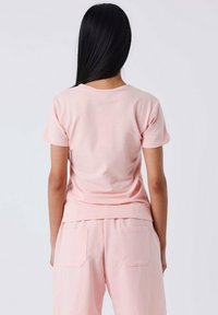 Camiseta de manga corta de color rosa claro, hecha de algodón suave, con un escote redondo y un corte relajado, con una textura lisa y un diseño minimalista.