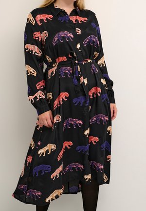 Czarna sukienka na guziki z długim rękawem ozdobiona kolorowymi czerwonymi, fioletowymi i beżowymi wzorami w cętki oraz przewiązanym paskiem w talii.