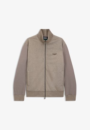 Veste beige et taupe zippée avec col montant, manches longues, poches latérales et petit logo brodé sur la poitrine gauche.