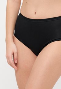 Black cotton high-waisted brief with a smooth texture, elastic waistband, and rounded leg openings, displaying a minimalist design.