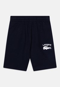 Mörkblå bomullsshorts med resårmidja, prydda med vit broderad Lacoste-logotyp och krokodilaccent på vänster ben.