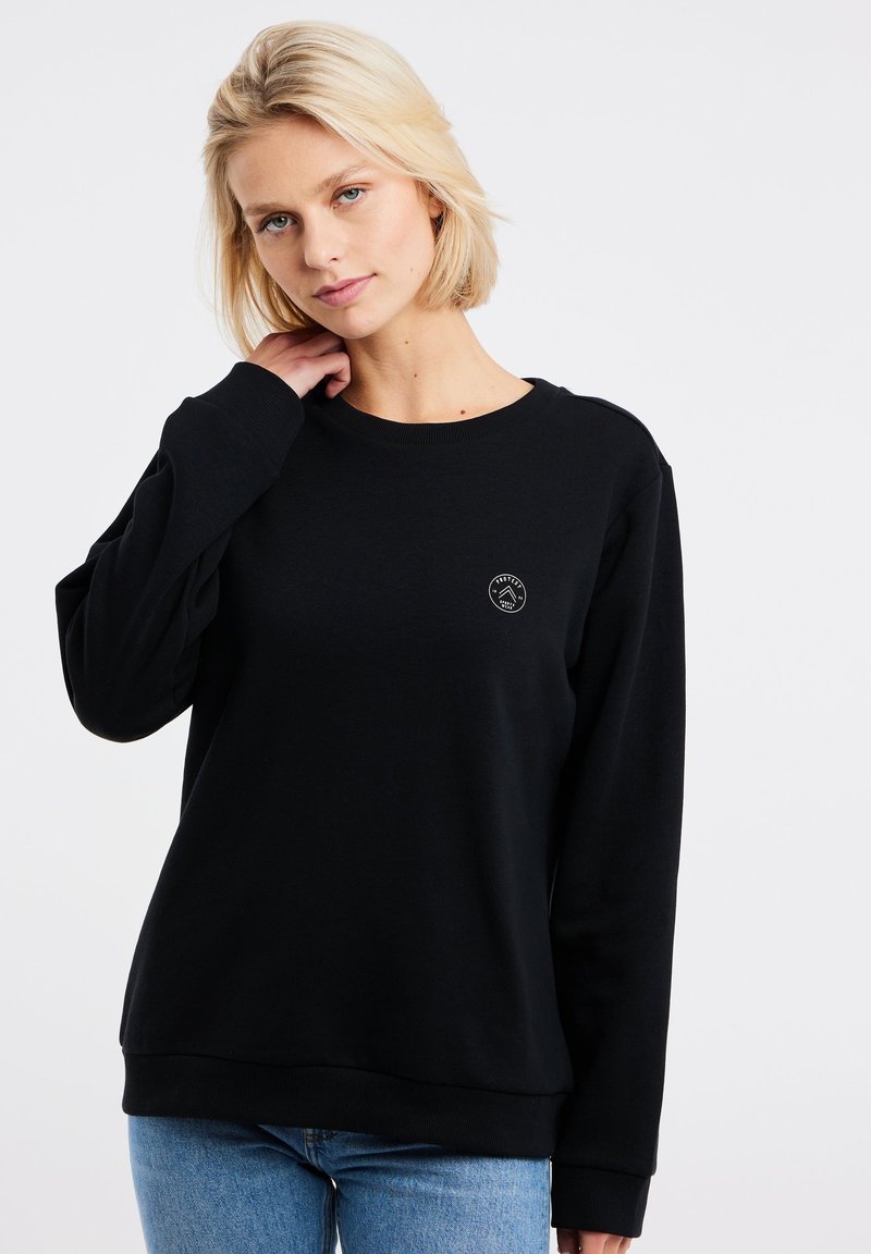 Zwarte crewneck sweatshirt gemaakt van een zachte stof, met een klein rond logo op de borst. Lange mouwen en een relaxte pasvorm.