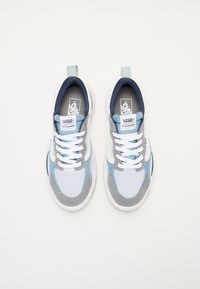 Ténis em azul claro, cinza e branco. Materiais em malha e camurça, design de atar, ponta arredondada, com uma aba na parte de trás e logótipo da Vans.