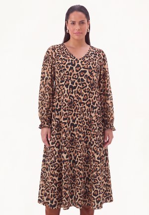 Kvinde iført en langærmet leopardprint kjole til knæet med V-udskæring og rynkede manchetter, stående mod en ensfarvet hvid baggrund.