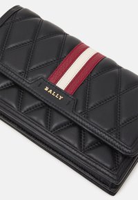 Portefeuille en cuir matelassé noir avec détail de rayure rouge et blanche, doté du logo doré "BALLY" sur le rabat avant.