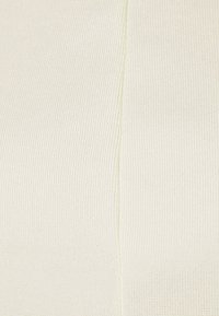 Light beige fabric with a ribbed texture, featuring a visible seam detail. The material appears soft and slightly stretchy.