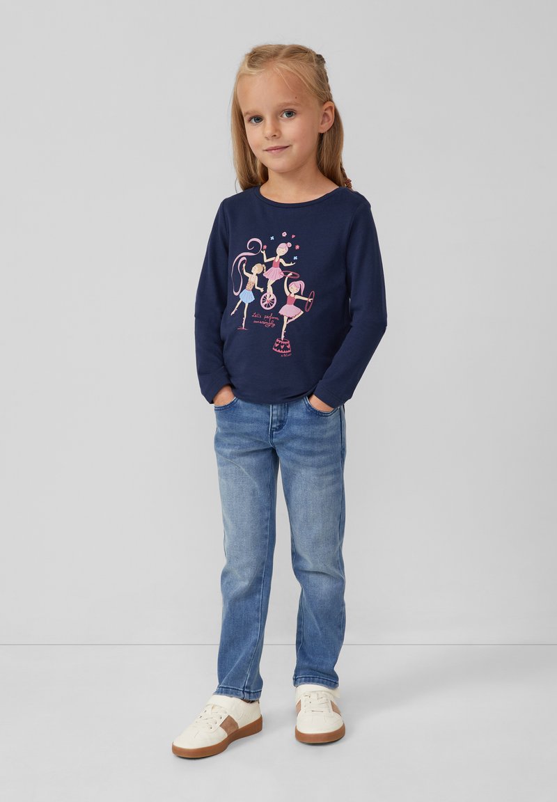 Marineblaue Langarm-T-Shirt mit pinkem Cartoon-Design, blaue Jeans und weiße Sneakers mit braunen Akzenten; glatte Textur und lässige Passform.