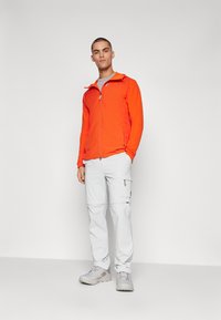 Lightweight orange zip-up jacket, gray T-shirt underneath, paired with light gray cargo pants and gray hiking shoes. Smooth texture, functional design.