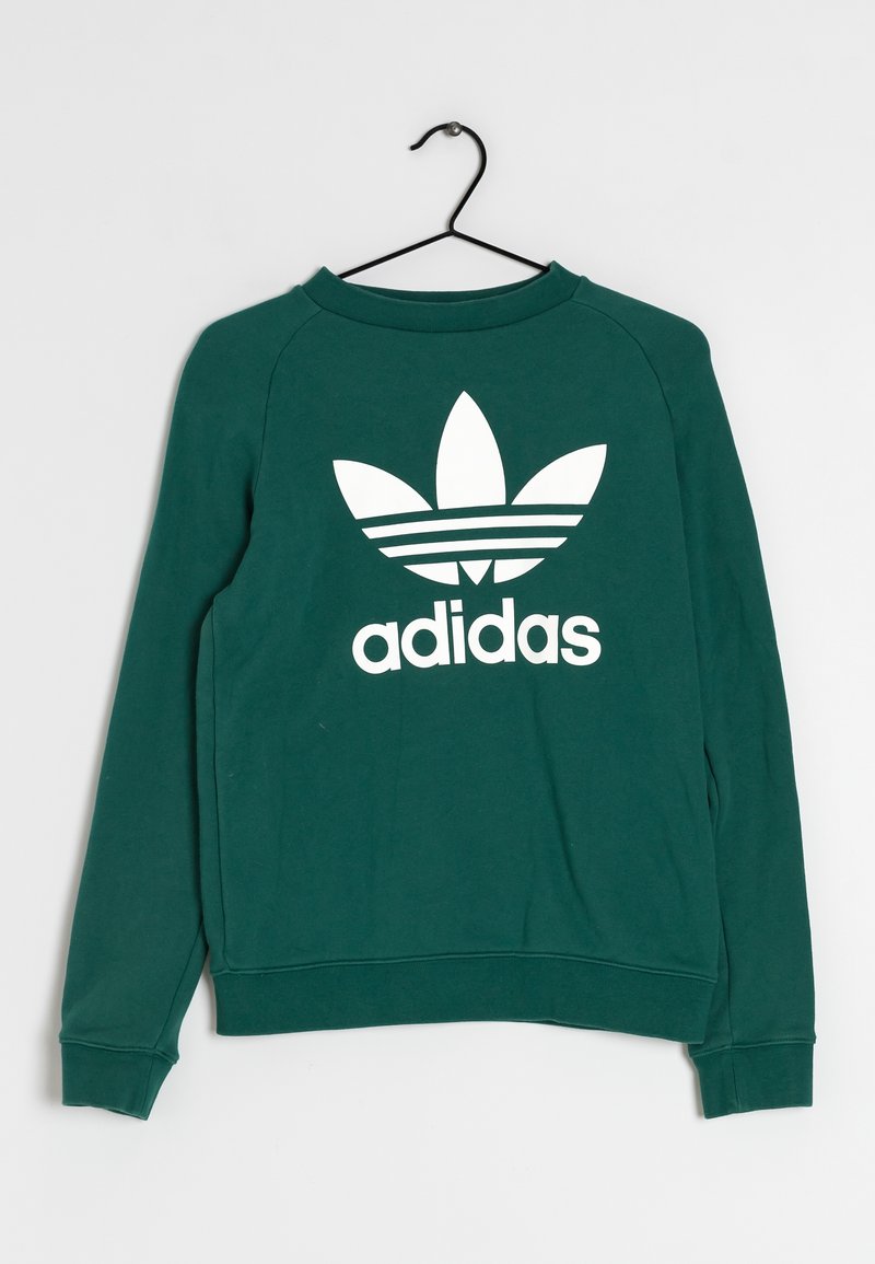 Sweatshirt vert à manches longues, avec des poignets et un ourlet côtelés, présentant un grand logo trefoil blanc d'Adidas à l'avant. Matière en coton lisse.