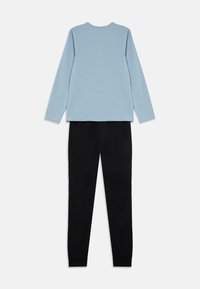 Langermet lys blå topp med rund hals og svarte bukser, mykt stoff med elastiske mansjetter ved anklene. Enkel design uten mønstre.
