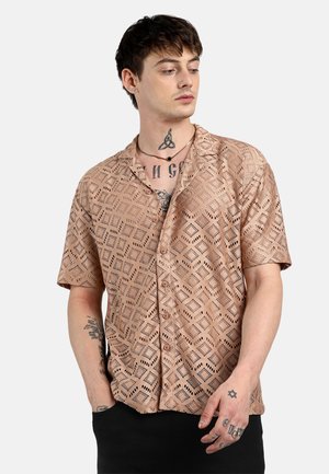 Camicia a maniche corte di colore marrone chiaro con un motivo a ritaglio geometrico, chiusura con bottoni sul davanti e vestibilità comoda. Tessuto morbido con una leggera lucentezza.