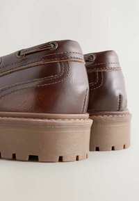 Ruske nahkasaappaat nilkkamittaisella hiotulla pinnalla, beige paksu pohja, teksturoidut yksityiskohdat ja metalliset nauha-aukot.