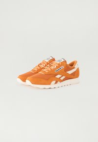 Oransje semsket lær sneakers med hvite detaljer, med en polstret såle, snøring og et logo-merke på tungen.