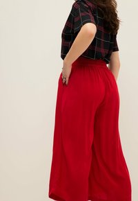 Rode wijde broek met een elastische tailleband, gemaakt van een lichtgewicht stof, met een gladde textuur en relaxed fit.