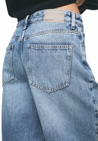 Jeans in denim azzurro chiaro con vestibilità comoda, caratterizzati da due tasche posteriori, un'etichetta in pelle del marchio Pull&Bear e una leggera scoloritura sul tessuto.