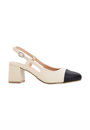 Scarpa beige con tacco a spillo slingback con punte nere, tacco quadrato e lati con aperture. Fascia alla caviglia regolabile con dettaglio in metallo.